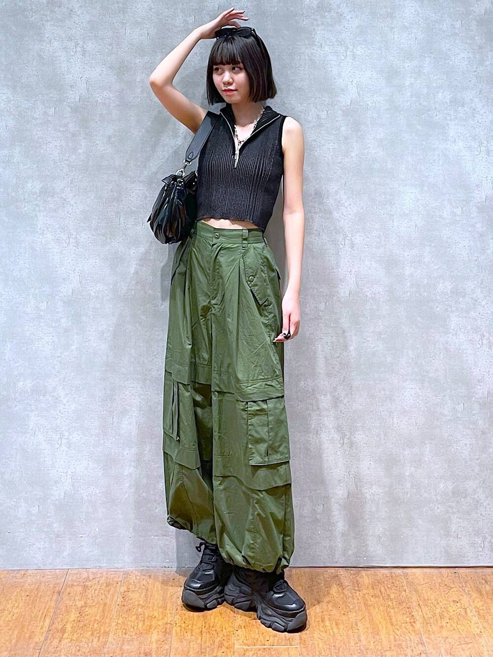 ブラック系のスニーカー、ブラック系のニット/セーター、グリーン系のその他パンツを着用したレディースの夏コーディネートの2枚目の写真