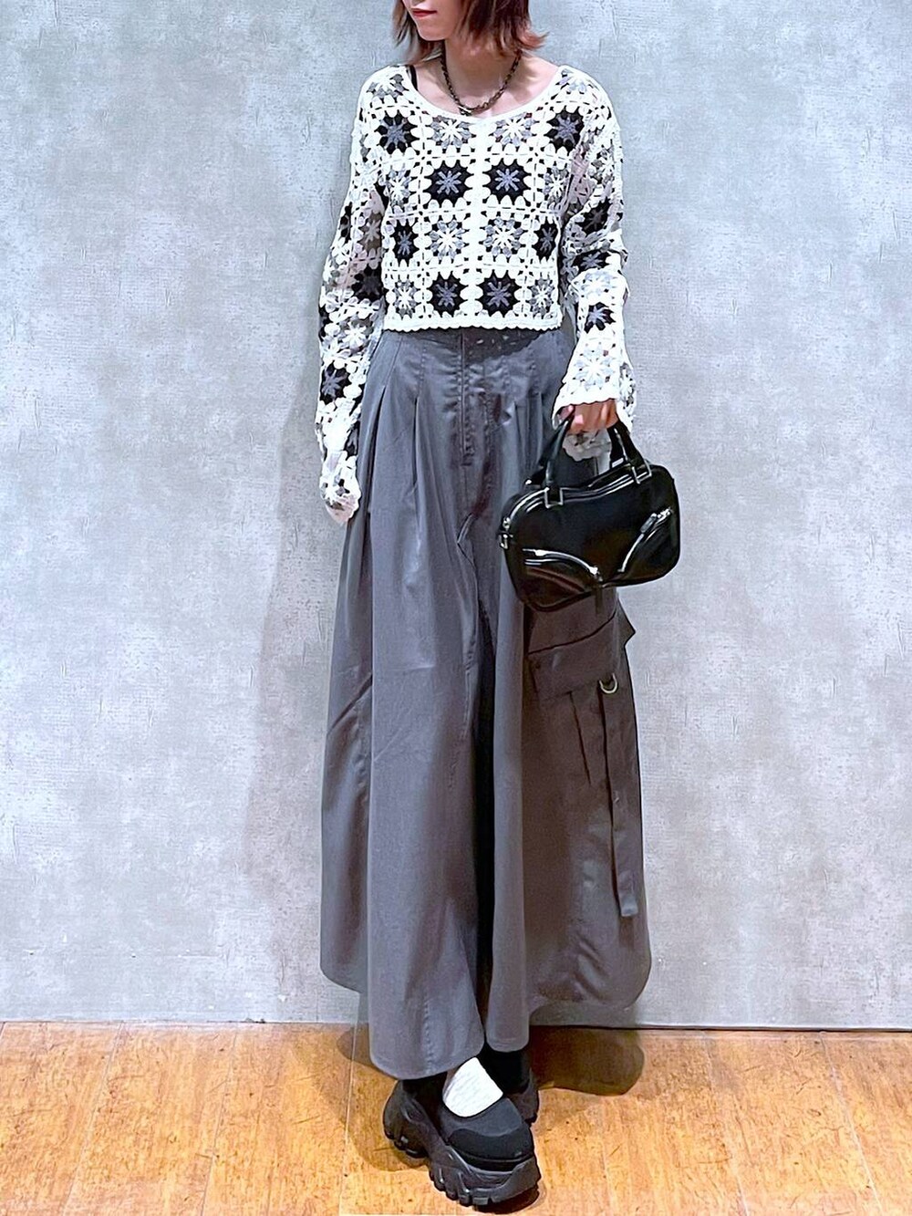 ホワイト系のカーディガン/ボレロ、ブラック系のキャミソール、グレー系のジャンパースカートを着用したレディースの春コーディネートの3枚目の写真