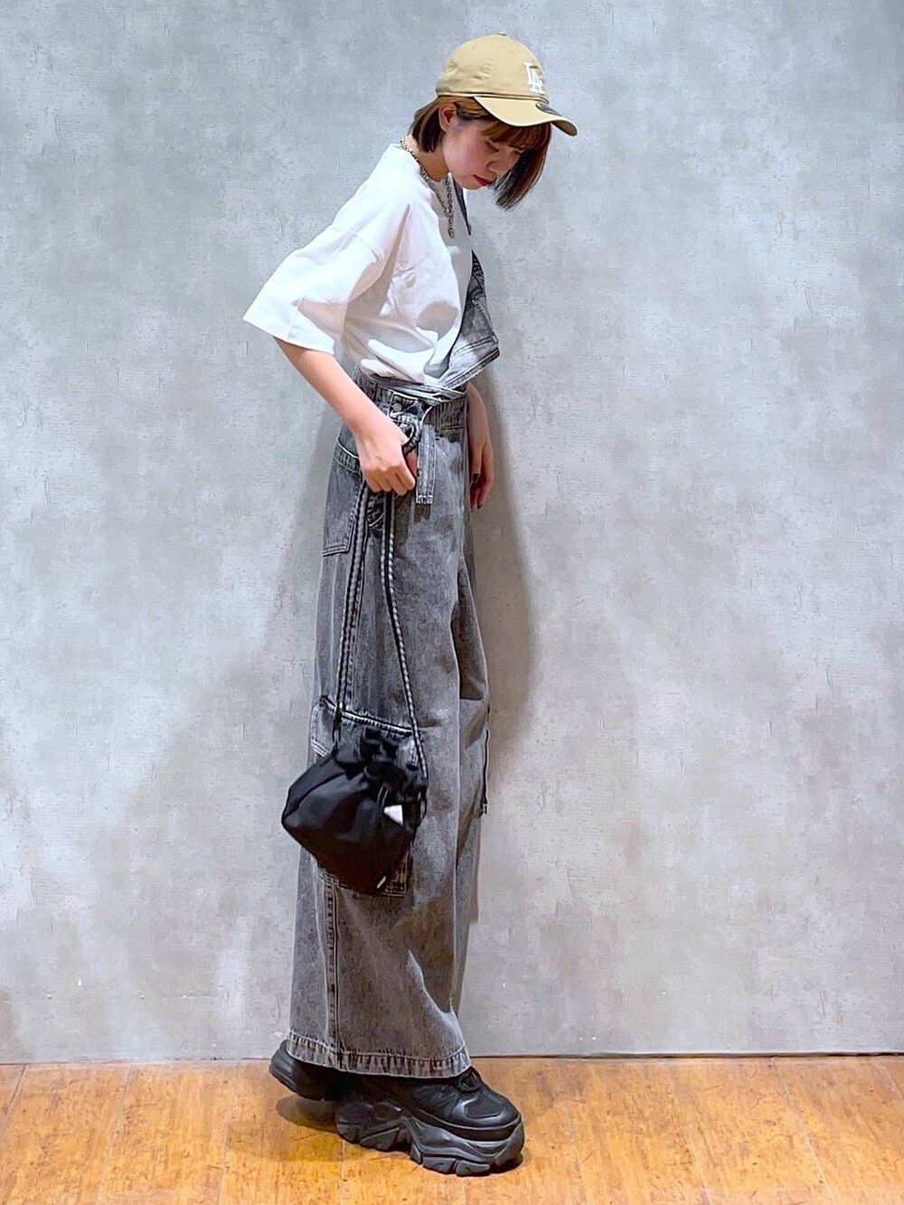 ブラック系のスニーカー、ブラック系のショルダーバッグ、ホワイト系のTシャツ/カットソーを着用したレディースの夏コーディネートの6枚目の写真