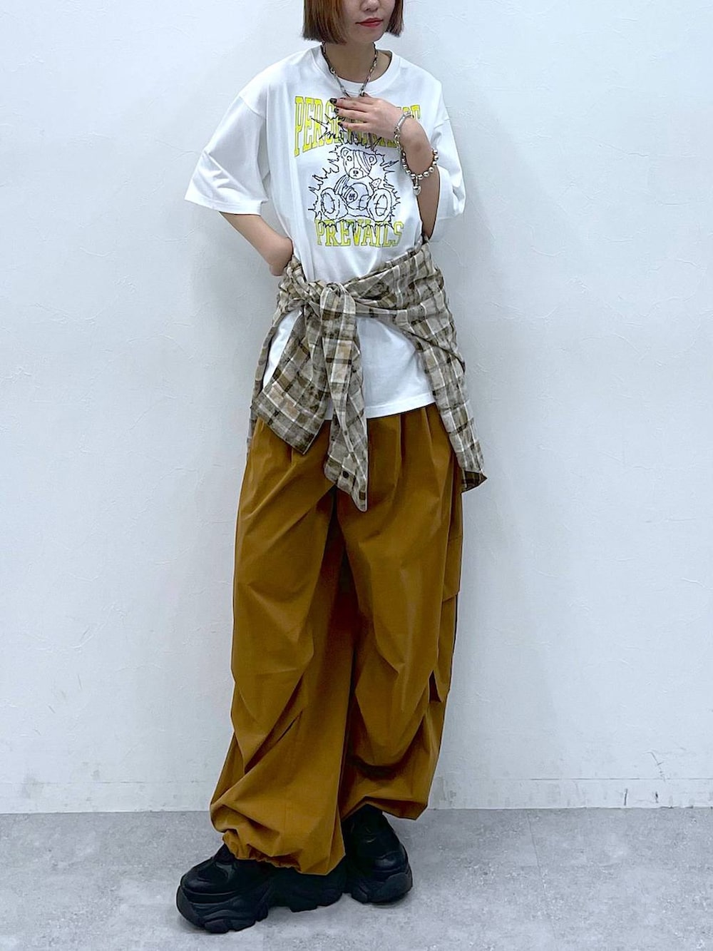 ブラック系のスニーカー、ブラウン系のカーゴパンツ、ホワイト系のTシャツ/カットソーを着用したレディースの夏コーディネートの3枚目の写真