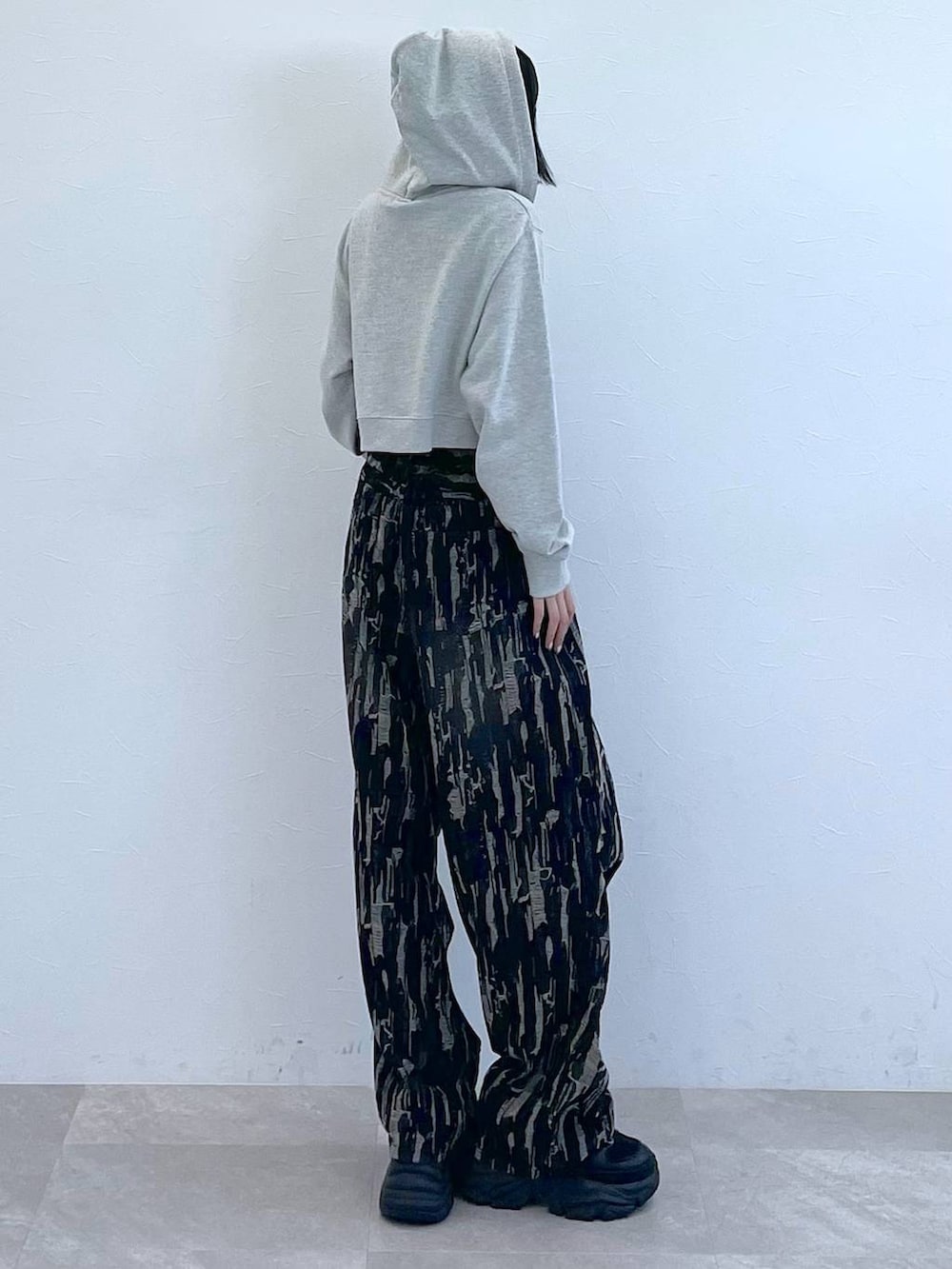 グレー系のパーカー、ホワイト系のキャミソール、ブラック系のスニーカーを着用したレディースの秋コーディネートの3枚目の写真