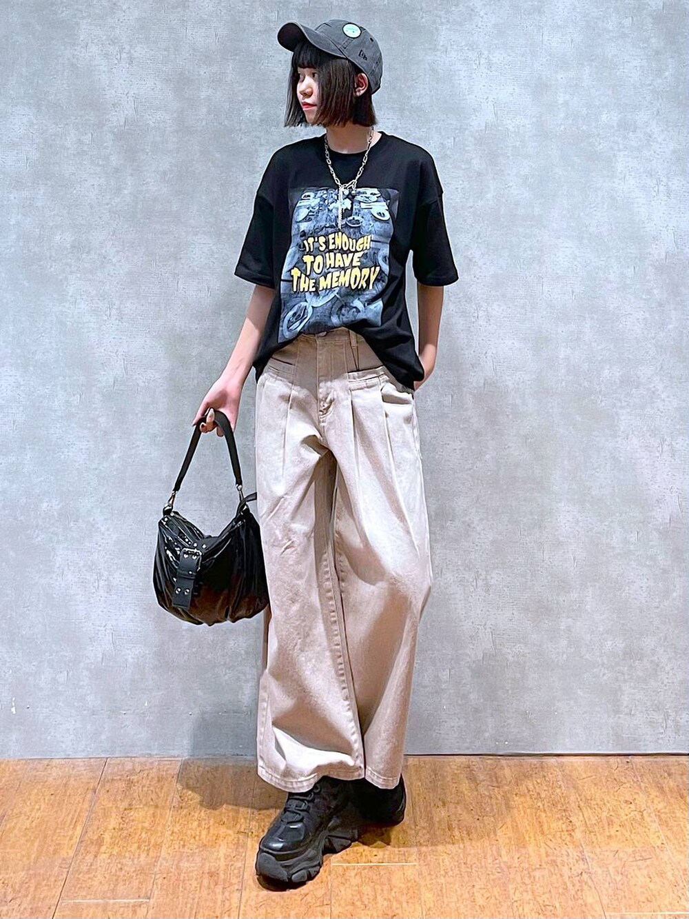 ブラック系のスニーカー、ブラック系のショルダーバッグ、ベージュ系のデニムパンツを着用したレディースの夏コーディネートの2枚目の写真