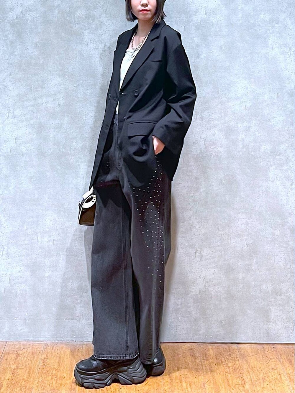 ブラック系のスニーカー、ブラック系のデニムパンツ、ブラック系のショルダーバッグを着用したレディースの秋コーディネートの3枚目の写真