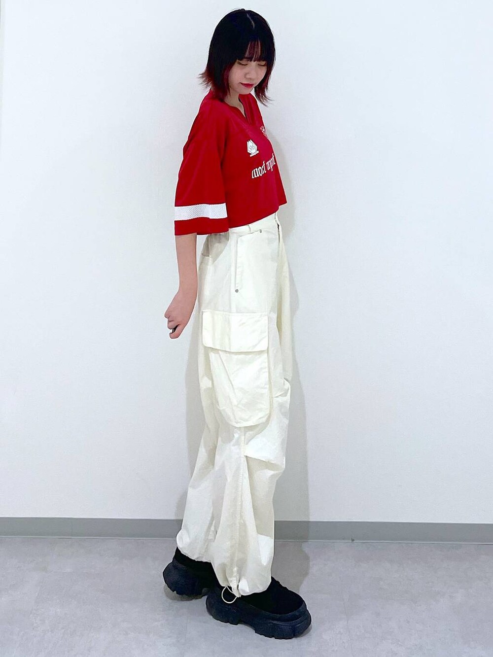 ホワイト系のカーゴパンツ、ブラック系のブーツ、レッド系のTシャツ/カットソーを着用したレディースの春コーディネートの3枚目の写真