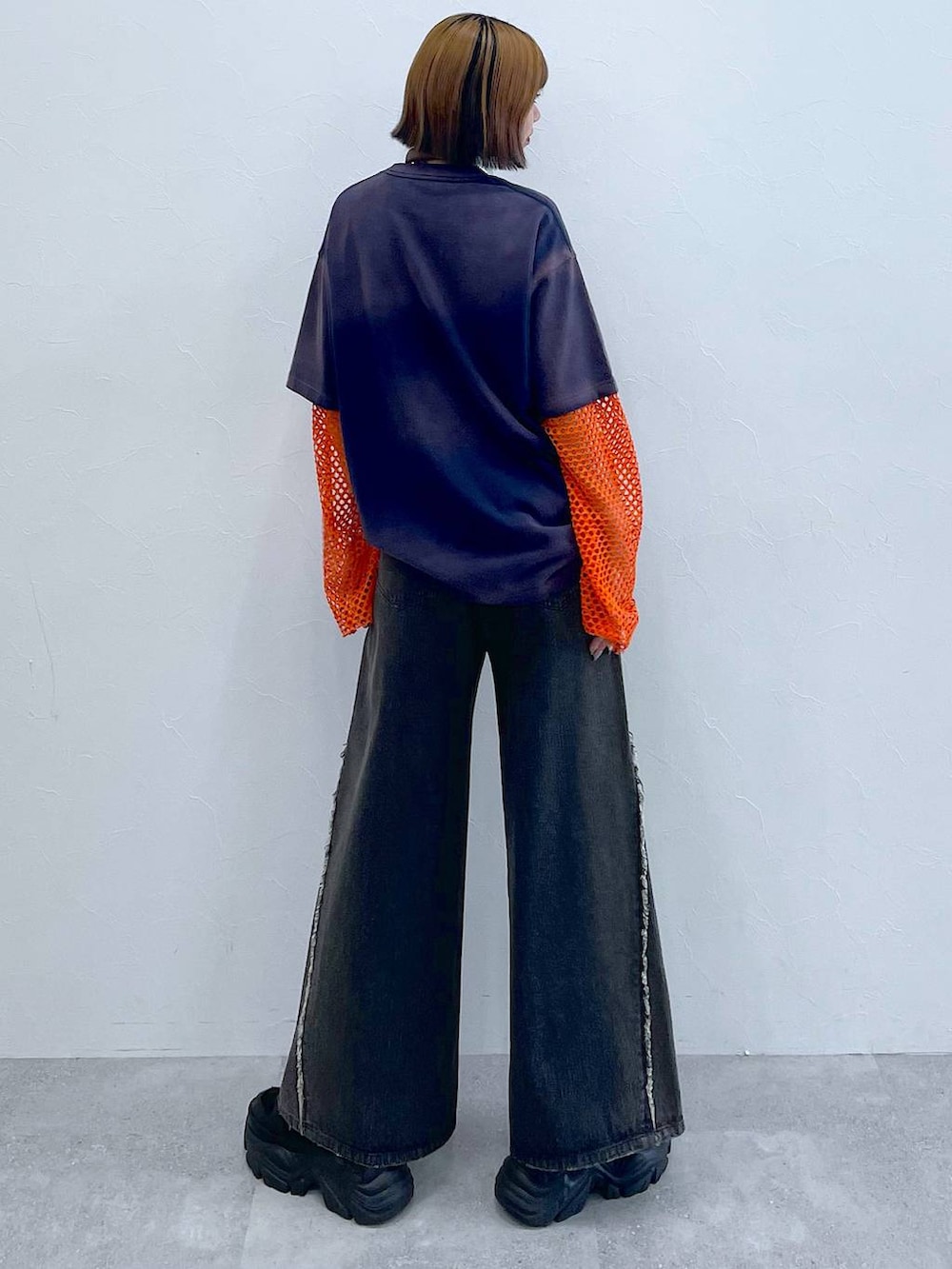 ブラック系のスニーカー、オレンジ系のTシャツ/カットソー、ブラック系のデニムパンツを着用したレディースの夏コーディネートの7枚目の写真