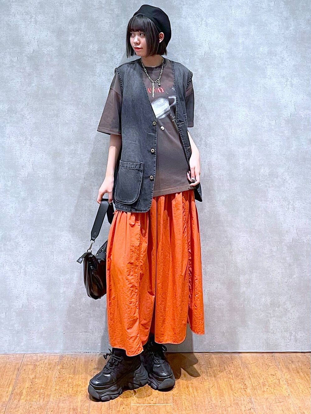 ブラック系のスニーカー、ブラック系のショルダーバッグ、オレンジ系のスカートを着用したレディースの夏コーディネートの3枚目の写真