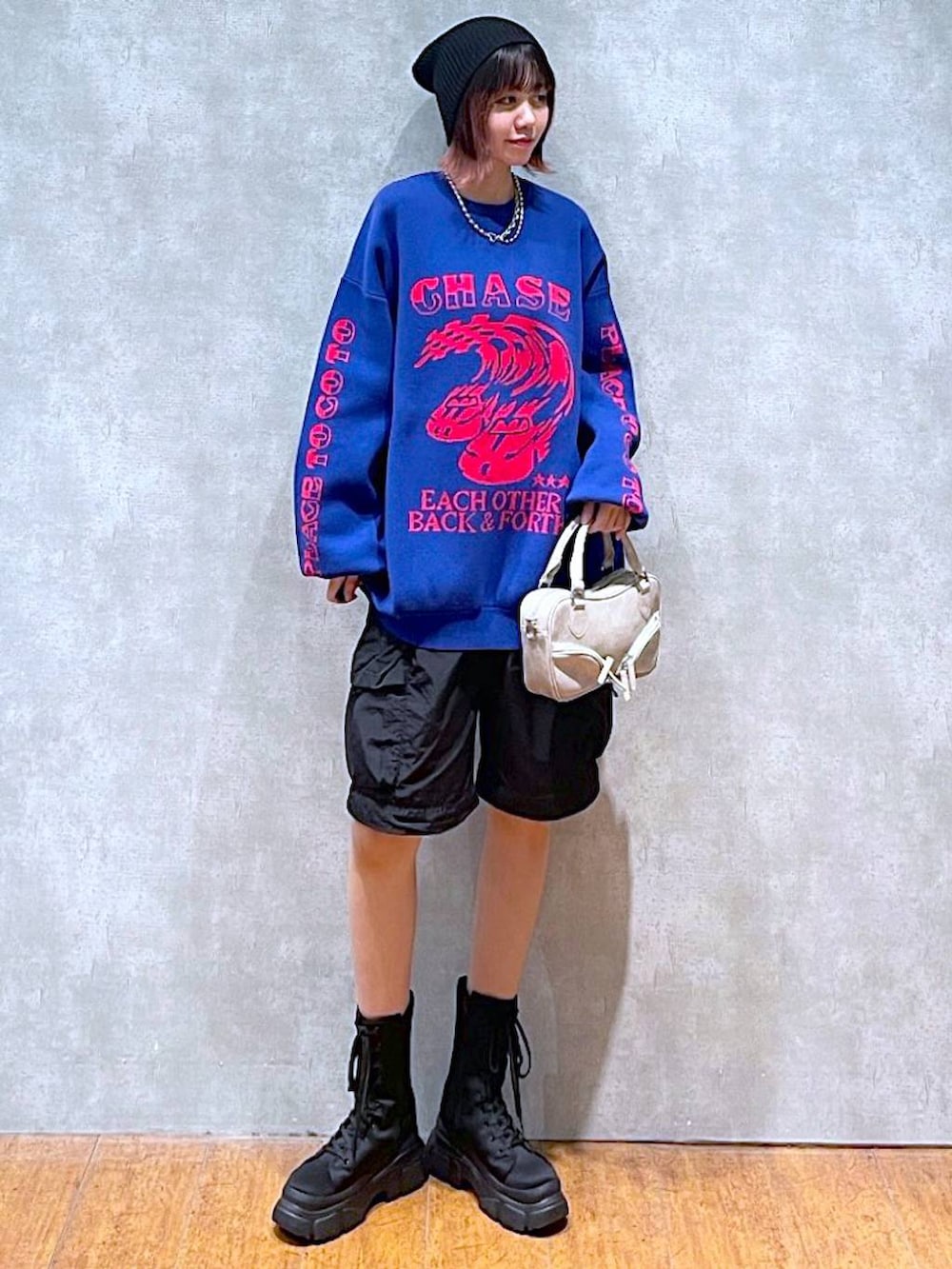 ブラック系のカーゴパンツ、ブルー系のニット/セーター、ベージュ系のボストンバッグを着用したレディースの冬コーディネートの2枚目の写真