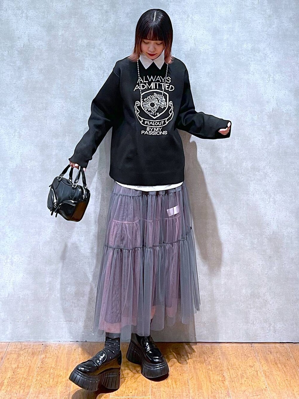 ブラック系のニット/セーター、ホワイト系のシャツ/ブラウス、グレー系のスカートを着用したレディースの春コーディネートの4枚目の写真