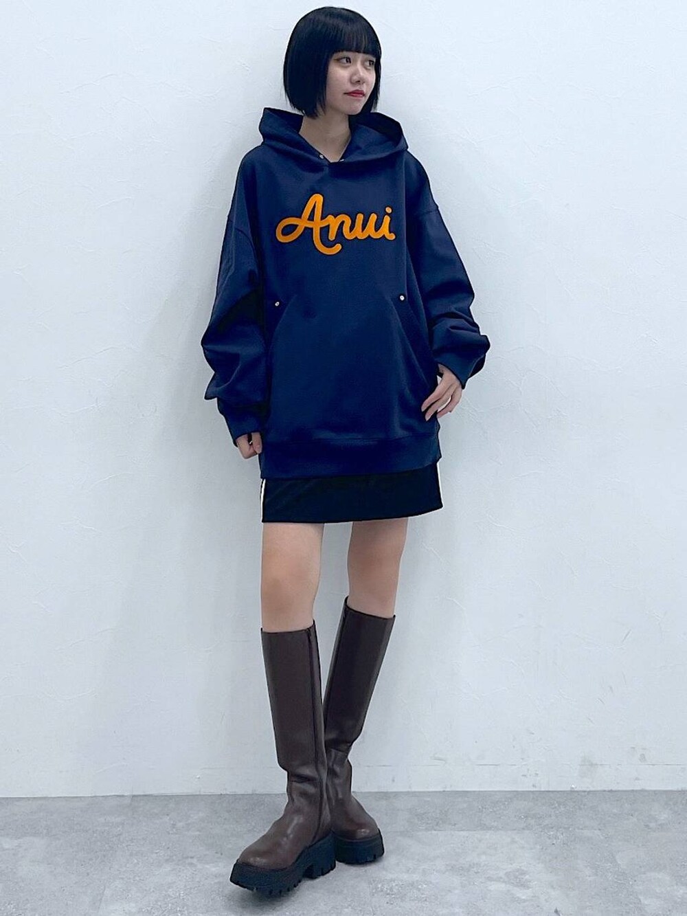 ブルー系のパーカー、ブラウン系のブーツ、ブラック系のスカートを着用したレディースの冬コーディネートの3枚目の写真