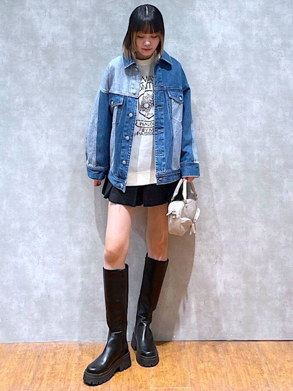 ホワイト系のニット/セーター、ブルー系のデニムジャケット、ブラック系のブーツを着用したレディースの冬コーディネートの2枚目の写真