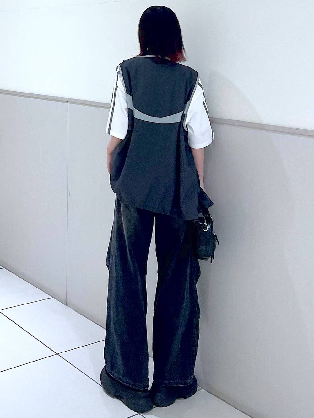 グレー系のベスト、ブラック系のデニムパンツ、ホワイト系のTシャツ/カットソーを着用したレディースの春コーディネートの5枚目の写真