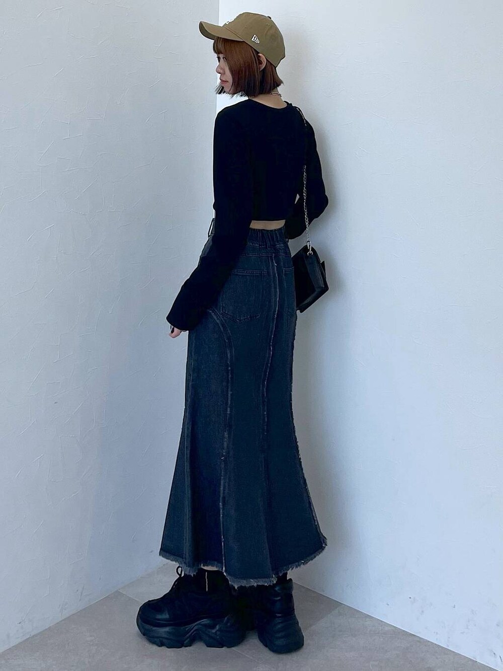 ブラック系のスニーカー、ブラック系のデニムスカート、ブラック系のTシャツ/カットソーを着用したレディースの秋コーディネートの5枚目の写真