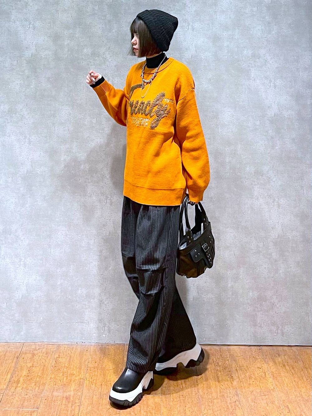 ブラック系のニット/セーター、ブラック系のデニムパンツ、ブラック系のハンドバッグを着用したレディースの秋コーディネートの3枚目の写真