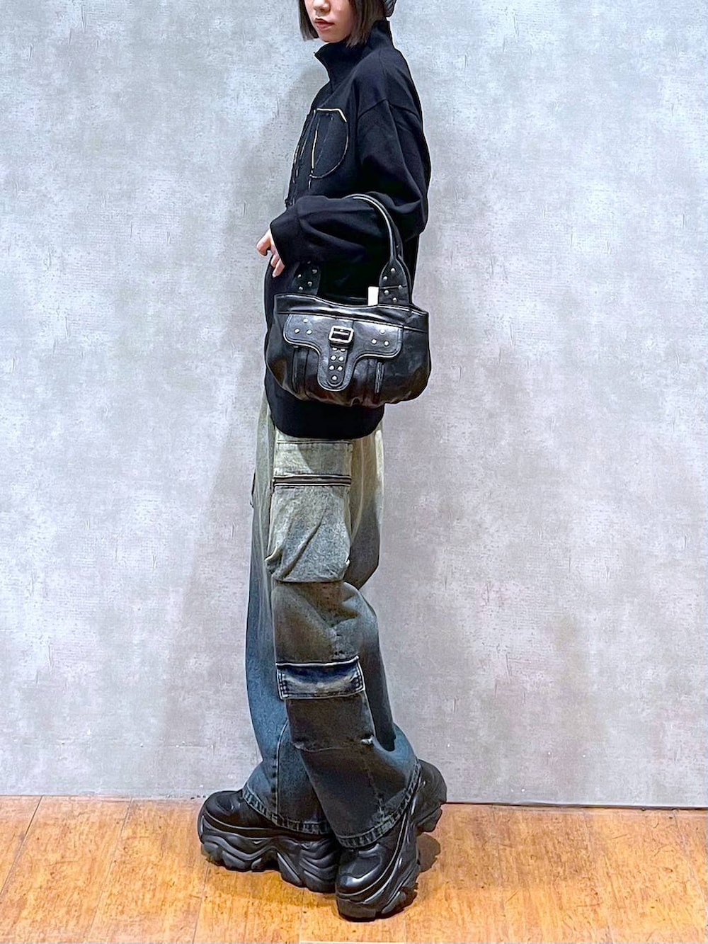 ブラック系のスニーカー、ブルー系のデニムパンツ、ブラック系のハンドバッグを着用したレディースの秋コーディネートの4枚目の写真