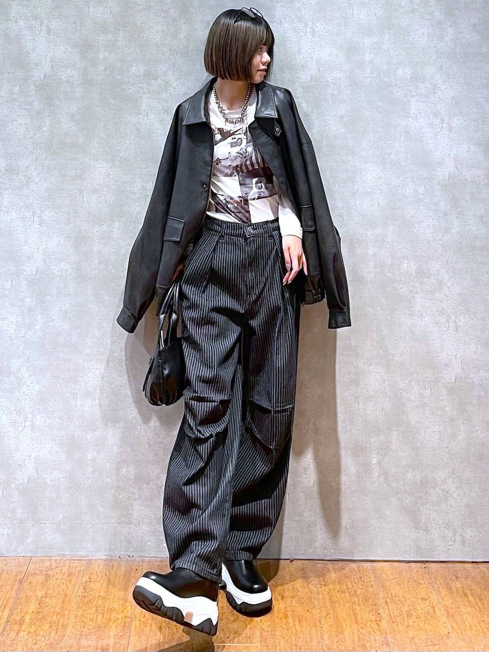 ブラック系のブルゾン、ブラック系のデニムパンツ、ブラック系のハンドバッグを着用したレディースの秋コーディネートの2枚目の写真