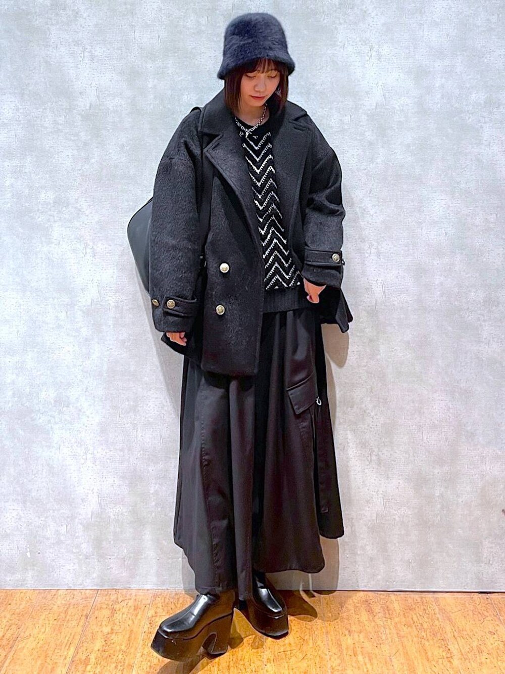 ブラック系のジャンパースカート、ブラック系のブーツ、ブラック系のショルダーバッグを着用したレディースの冬コーディネートの5枚目の写真