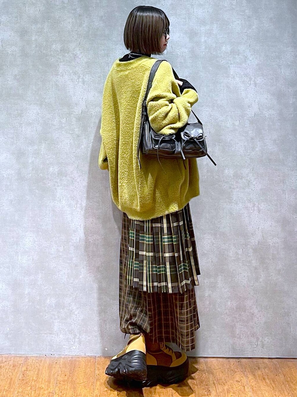 ブラック系のニット/セーター、ブラック系のショルダーバッグ、ブラウン系のブーツを着用したレディースの秋コーディネートの3枚目の写真