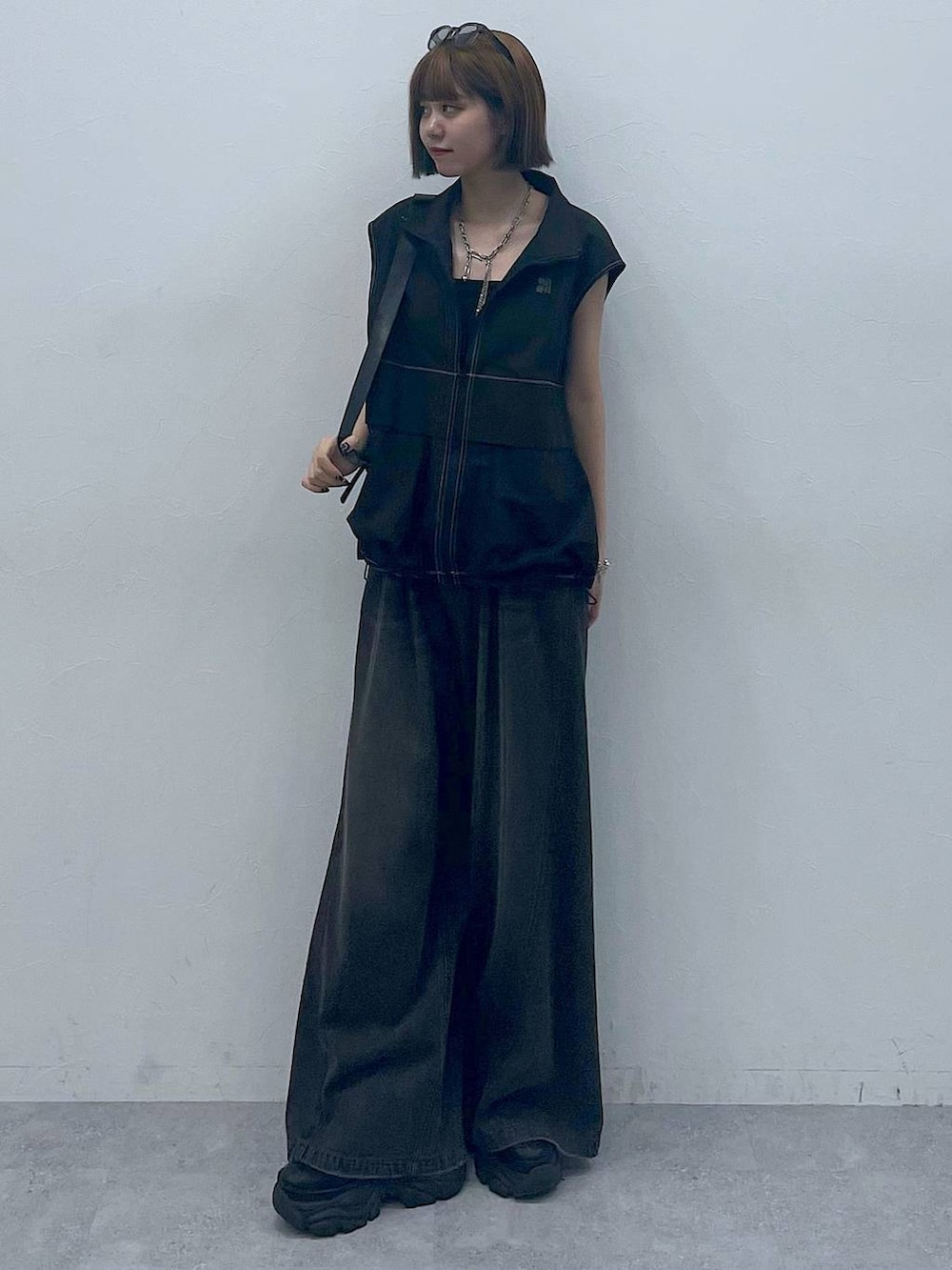 ブラック系のスニーカー、ブラック系のショルダーバッグ、ブラック系のデニムパンツを着用したレディースの夏コーディネートの5枚目の写真