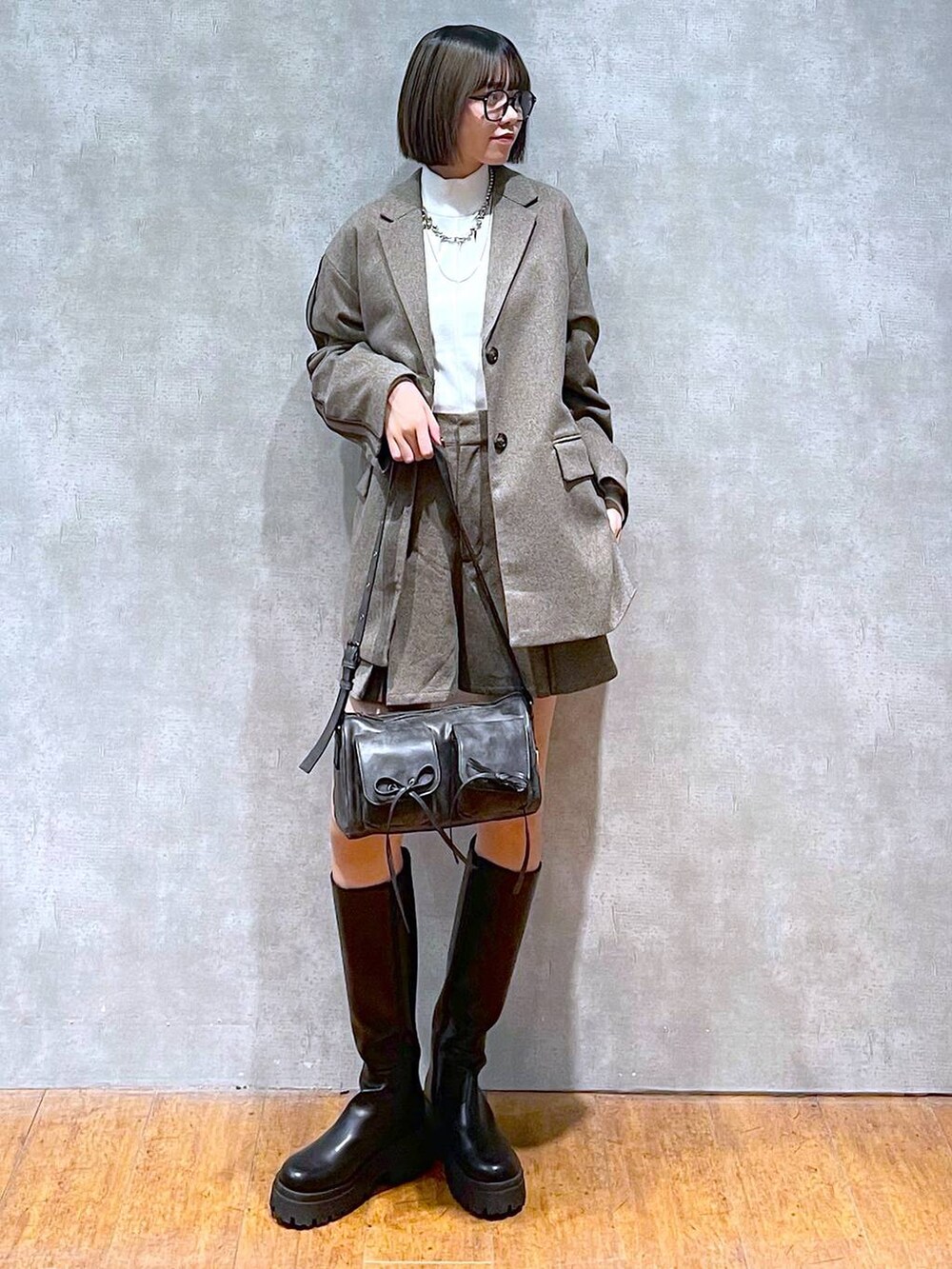 ブラック系のショルダーバッグ、ホワイト系のニット/セーター、ブラック系のブーツを着用したレディースの秋コーディネートの2枚目の写真