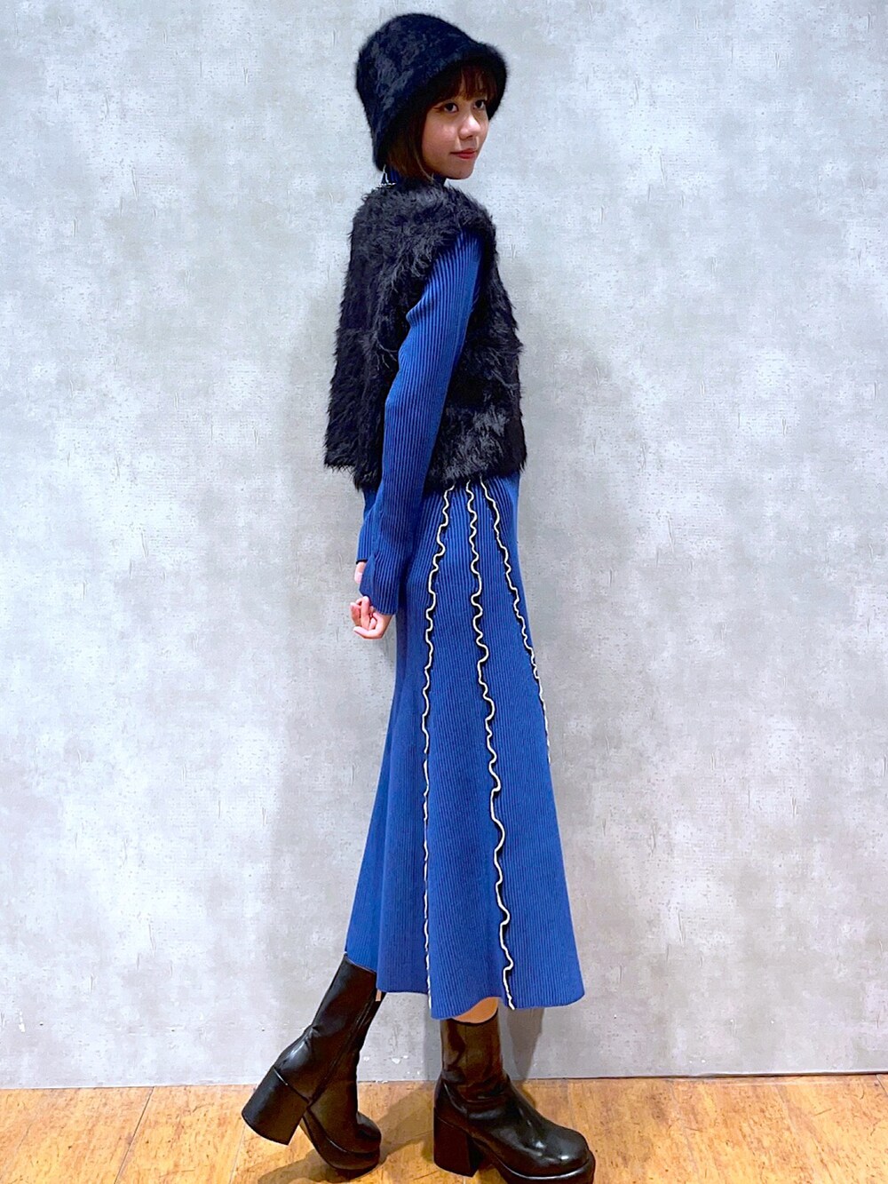 ブルー系のワンピース、ブラック系のベスト、ブラック系のブーツを着用したレディースの秋コーディネートの2枚目の写真