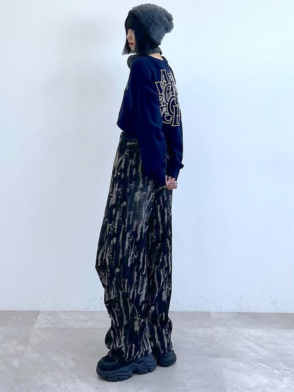 ブラック系のスニーカー、ブラック系のデニムパンツ、ホワイト系のキャミソールを着用したレディースの秋コーディネートの4枚目の写真