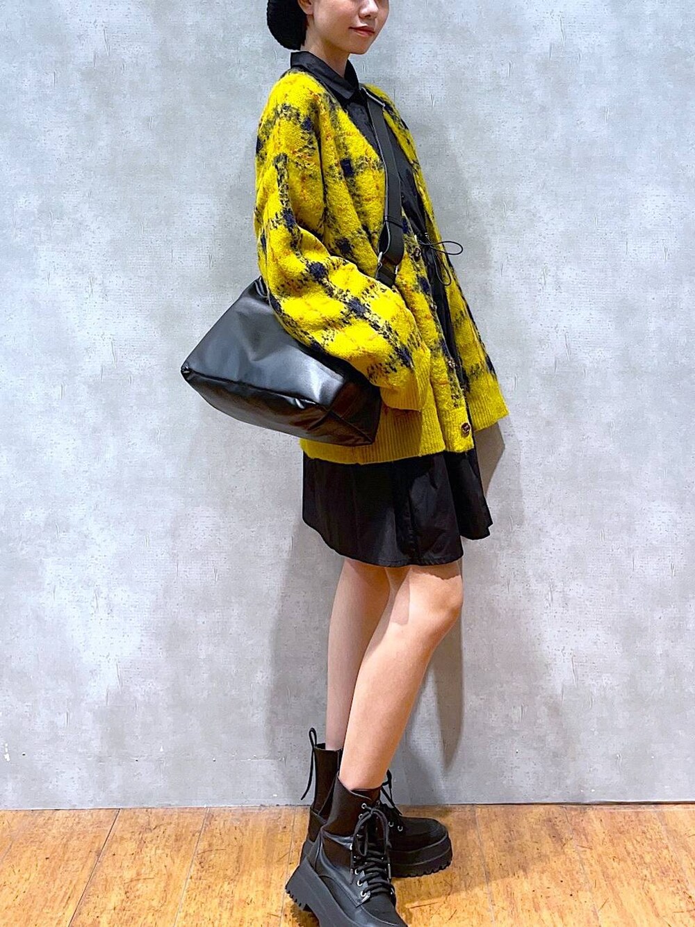 ブラック系のブーツ、イエロー系のカーディガン/ボレロ、ブラック系のショルダーバッグを着用したレディースの秋コーディネートの2枚目の写真