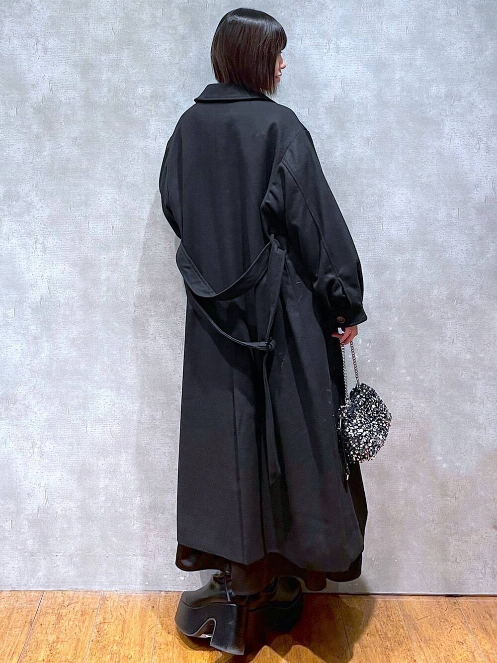 ブラック系のチェスターコート、ブラック系のブーツ、ブラウン系のニット/セーターを着用したレディースの冬コーディネートの3枚目の写真