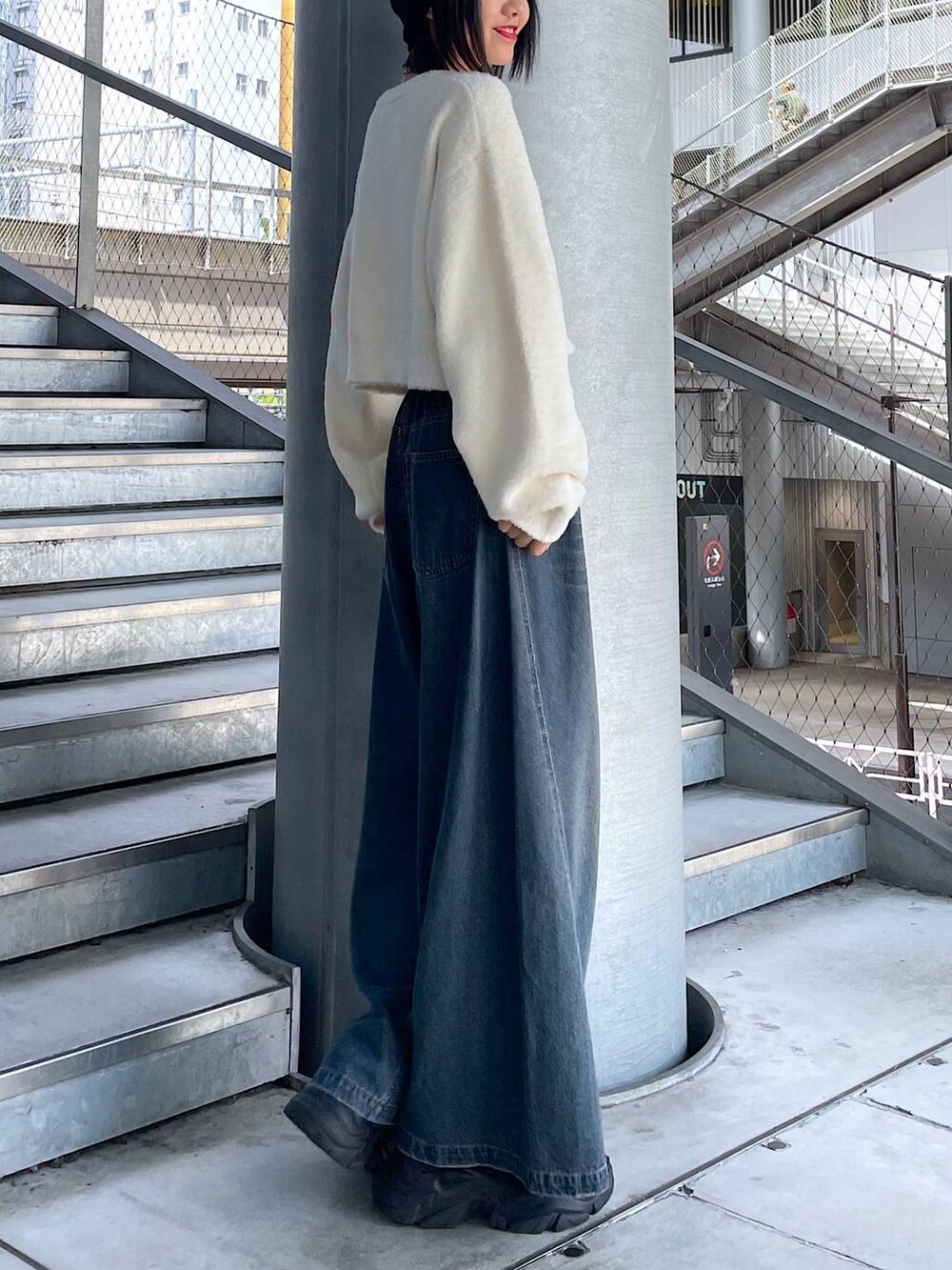 ブラック系のスニーカー、ブルー系のデニムパンツ、ホワイト系のニット/セーターを着用したレディースの秋コーディネートの3枚目の写真