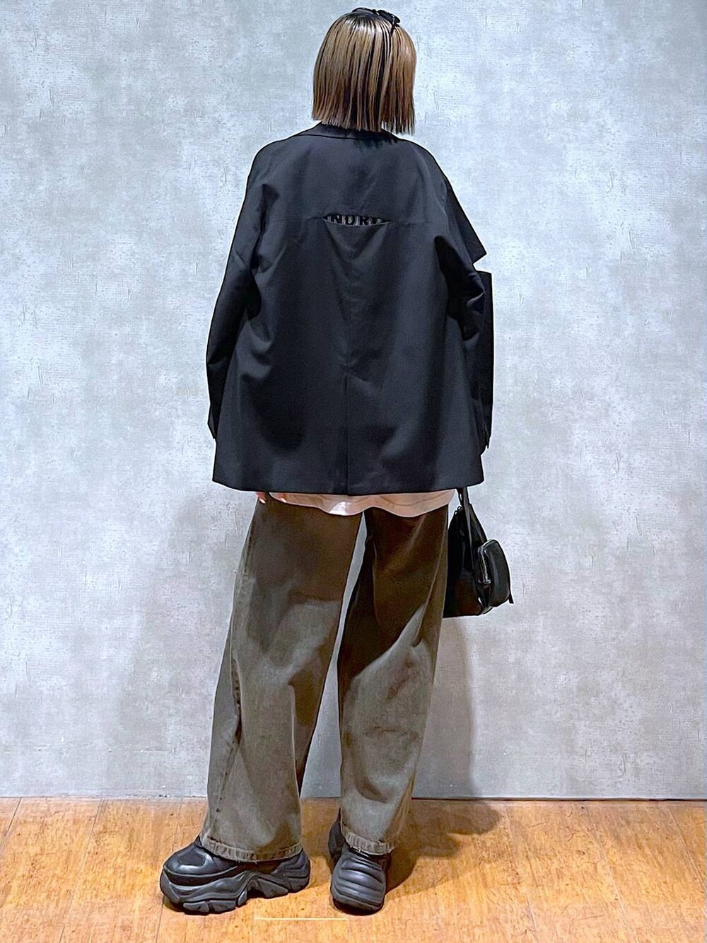 ブラック系のスニーカー、ベージュ系のTシャツ/カットソー、ブラック系のデニムパンツを着用したレディースの秋コーディネートの5枚目の写真