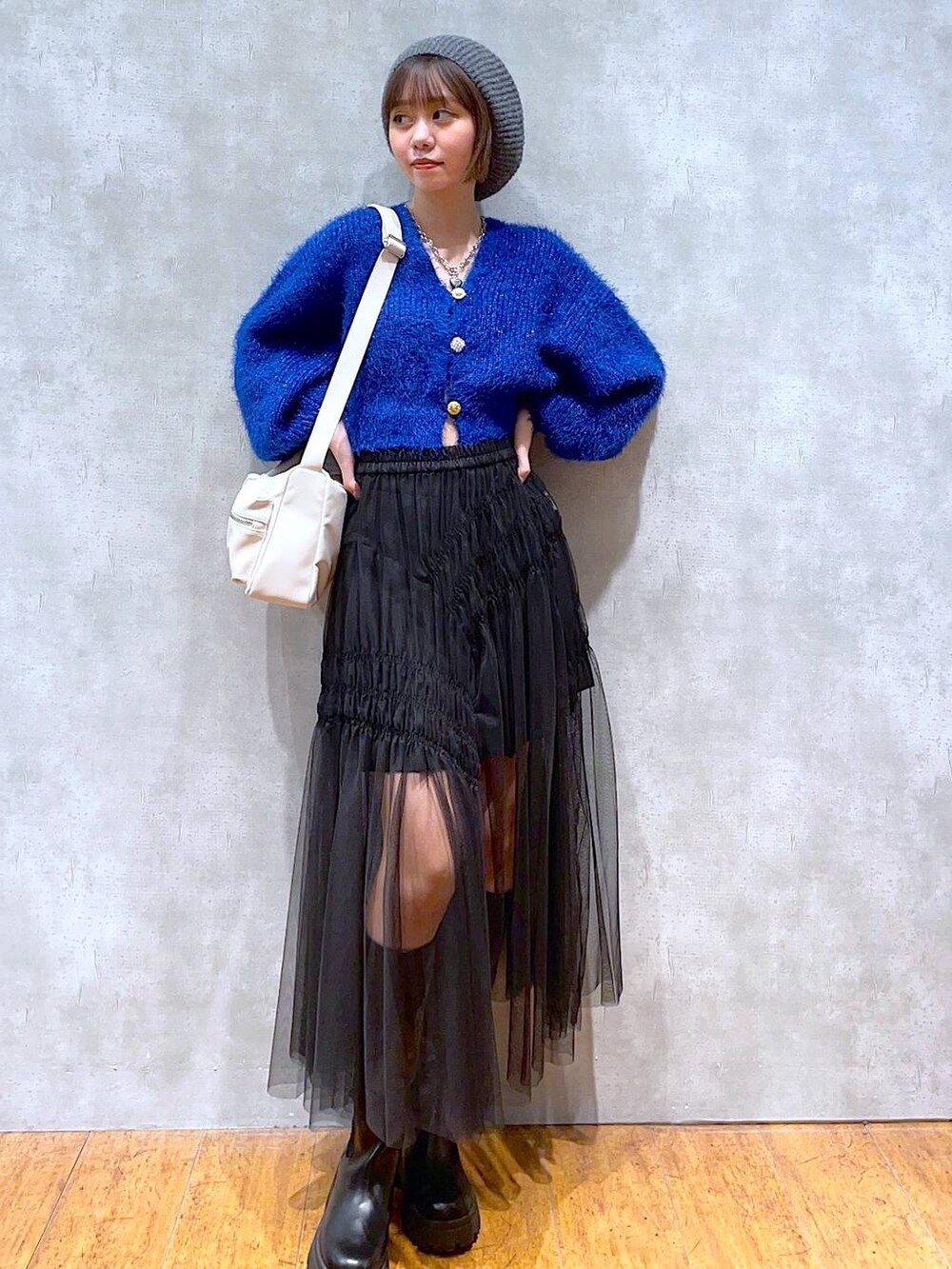 ホワイト系のショルダーバッグ、ブラック系のブーツ、ブルー系のカーディガン/ボレロを着用したレディースの秋コーディネートの3枚目の写真