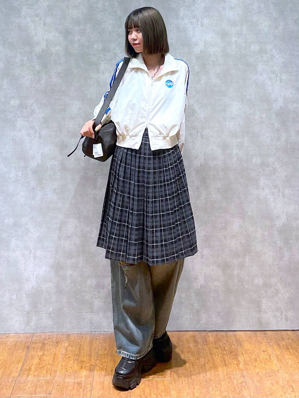 ブラック系のスニーカー、ブラック系のショルダーバッグ、ブルー系のデニムパンツを着用したレディースの秋コーディネートの2枚目の写真