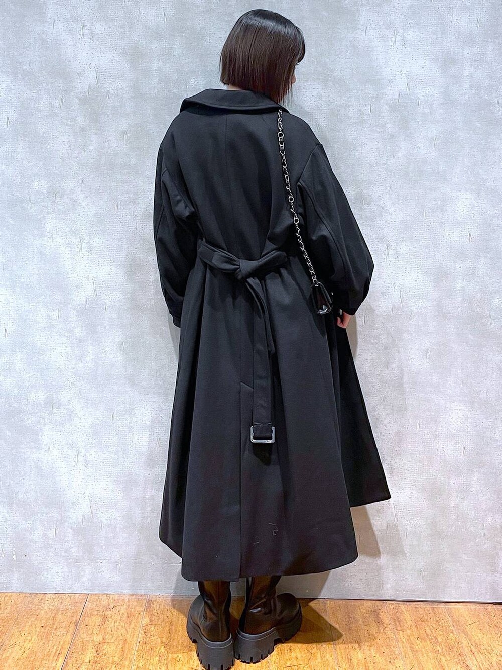 ブラック系のスカート、ブラック系のチェスターコート、ブラック系のブーツを着用したレディースの冬コーディネートの4枚目の写真