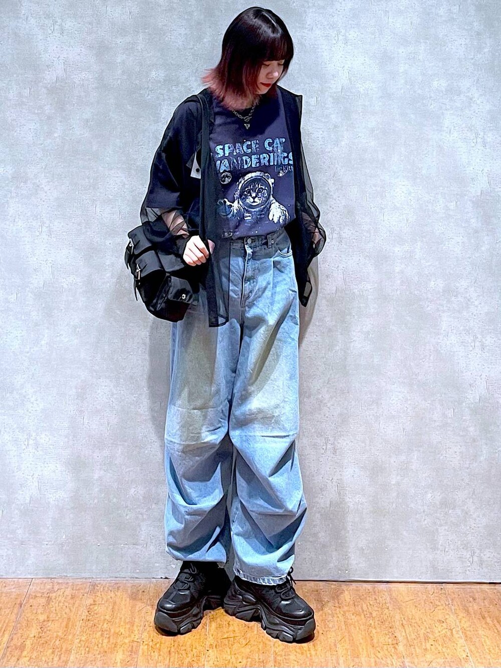 ブラック系のショルダーバッグ、ブルー系のデニムパンツ、ブラック系のスニーカーを着用したレディースの春コーディネートの2枚目の写真