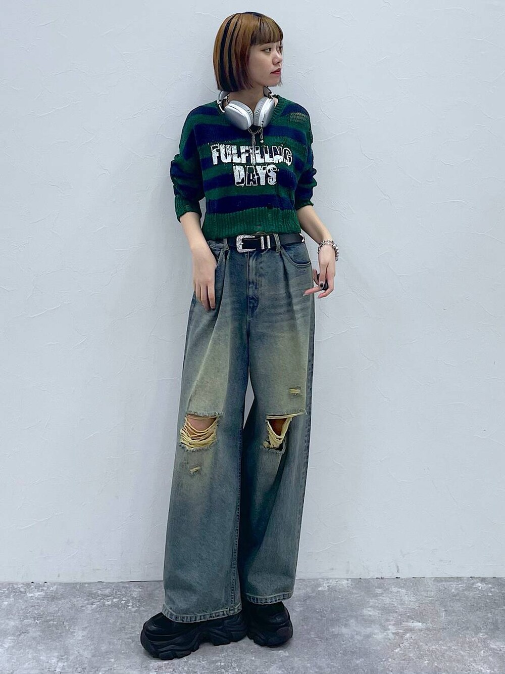 ブラック系のスニーカー、ブルー系のデニムパンツ、グリーン系のニット/セーターを着用したレディースの秋コーディネートの7枚目の写真