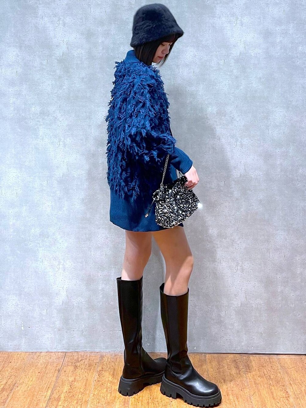 ブラック系のブーツ、ブラック系のニット/セーター、シルバー系のショルダーバッグを着用したレディースの冬コーディネートの4枚目の写真