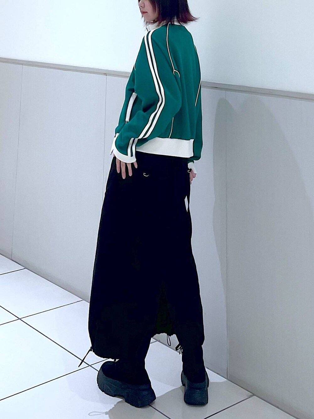 グリーン系のセットアップ、ブラック系のタンクトップ、ブラック系のブーツを着用したレディースの春コーディネートの6枚目の写真