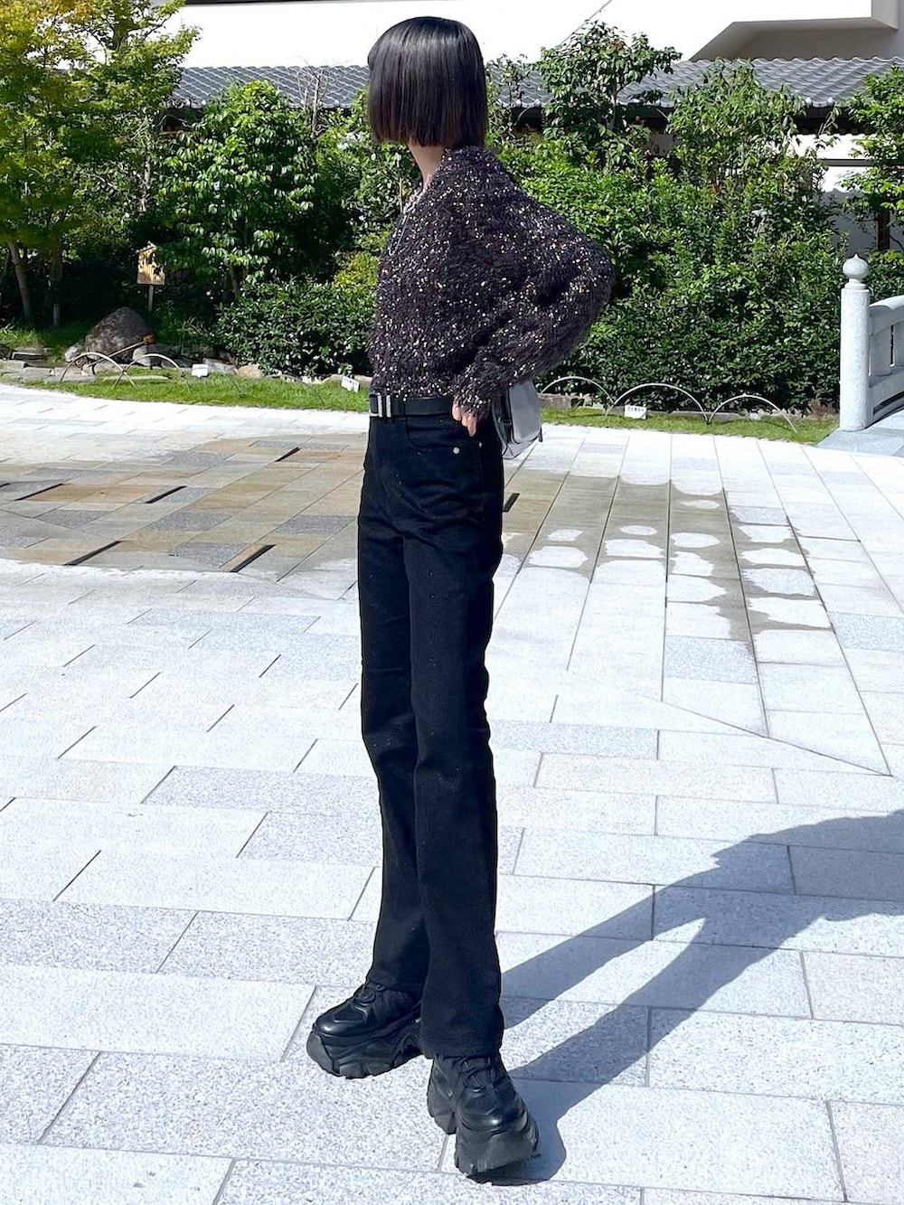 ブラック系のスニーカー、シルバー系のショルダーバッグ、ブラック系のニット/セーターを着用したレディースの秋コーディネートの2枚目の写真