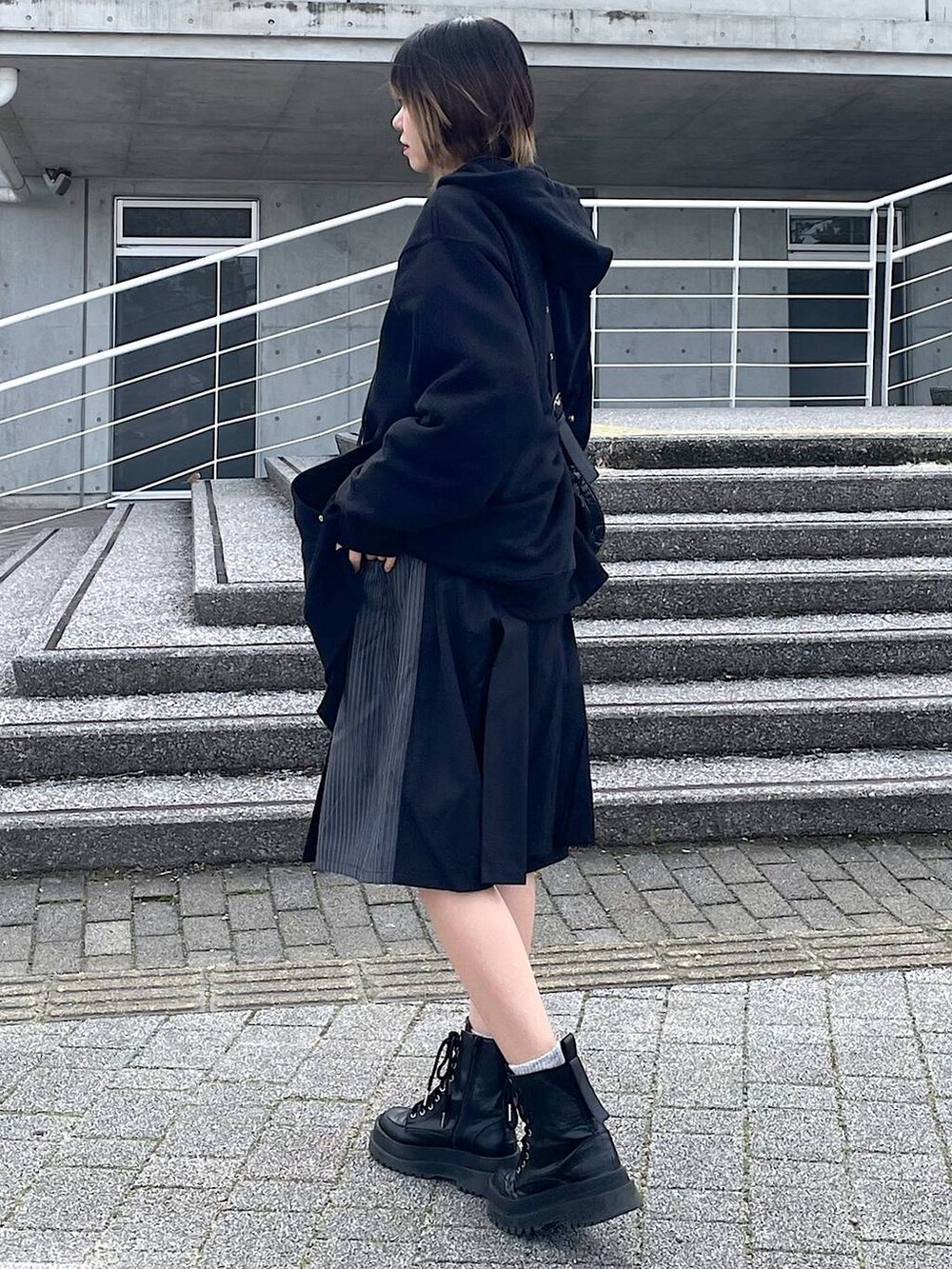 ブラック系のパーカー、ブラック系のショルダーバッグ、ブラック系のブーツを着用したレディースの冬コーディネートの7枚目の写真