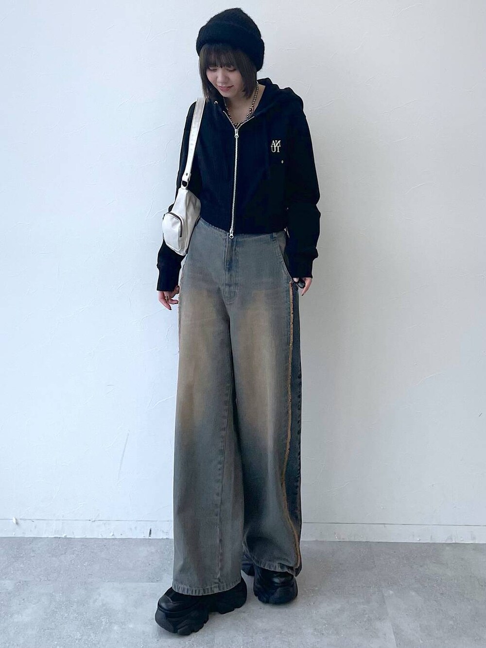 ブラック系のパーカー、ブラック系のスニーカー、ブルー系のデニムパンツを着用したレディースの秋コーディネートの4枚目の写真