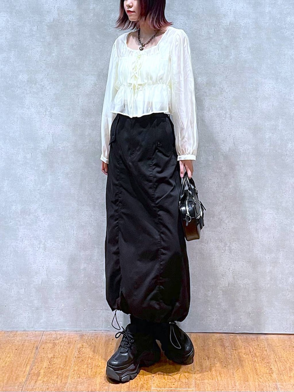 ブラック系のスニーカー、ベージュ系のシャツ/ブラウス、ホワイト系のキャミソールを着用したレディースの春コーディネートの3枚目の写真