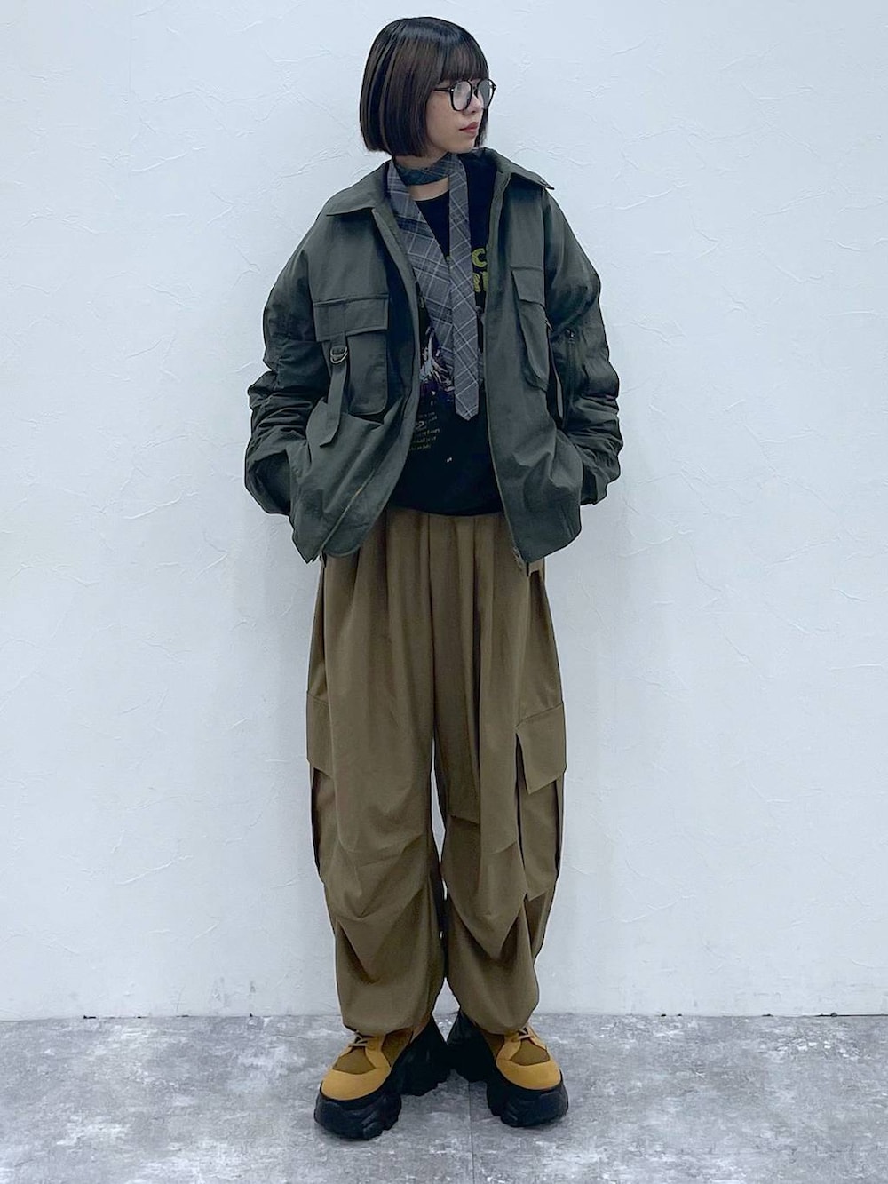 グレー系のネクタイ、ブラウン系のブーツ、グリーン系のブルゾンを着用したレディースの秋コーディネートの9枚目の写真