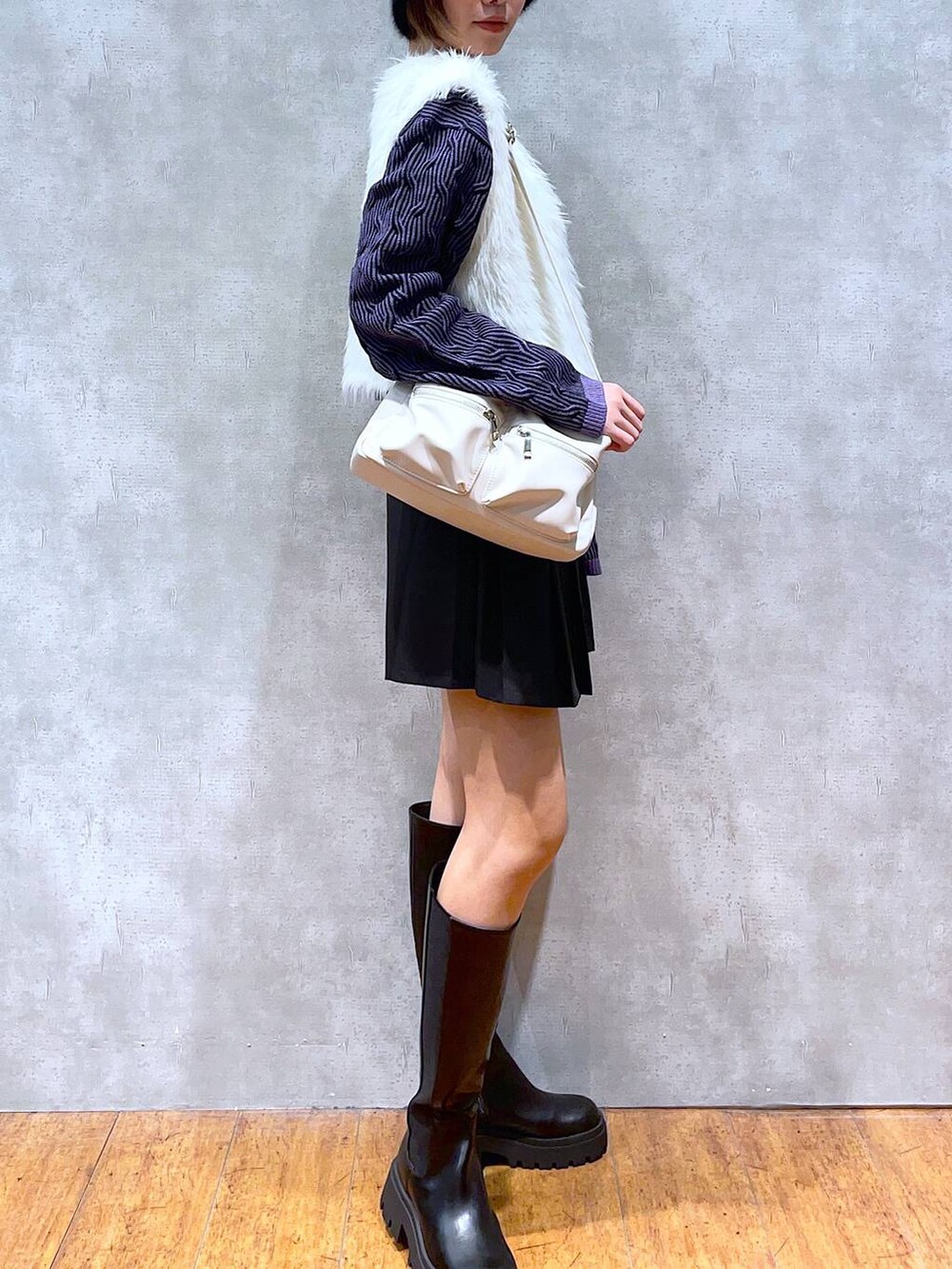 ホワイト系のショルダーバッグ、ブラック系のブーツ、ブラック系のスカートを着用したレディースの秋コーディネートの2枚目の写真