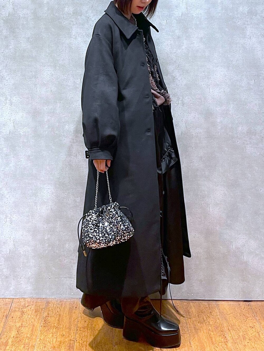 ブラック系のチェスターコート、ブラック系のブーツ、ブラウン系のニット/セーターを着用したレディースの冬コーディネートの2枚目の写真