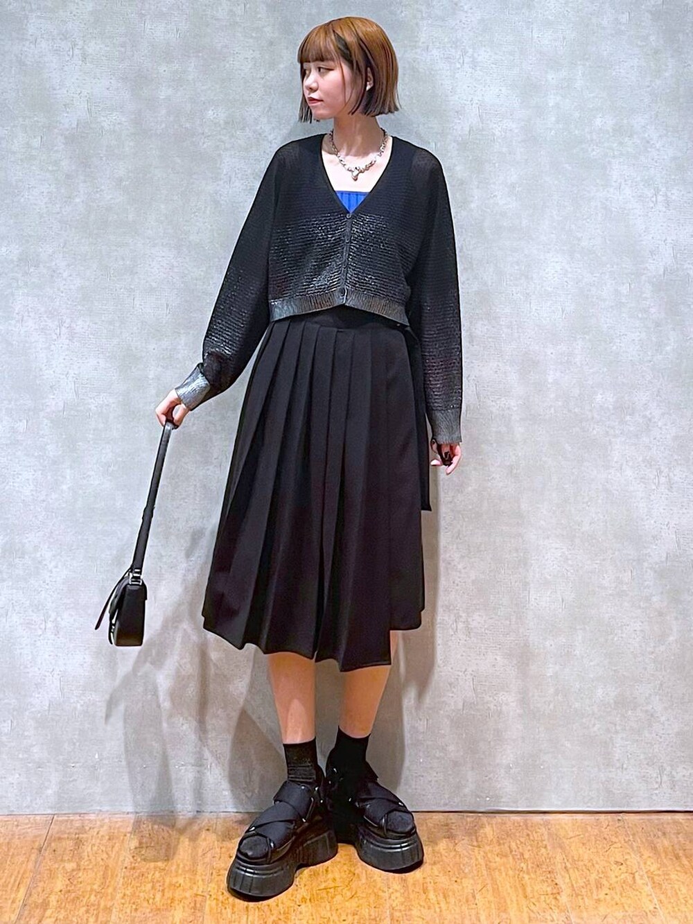 ブラック系のスニーカー、ブルー系のタンクトップ、ブラック系のスカートを着用したレディースの夏コーディネートの4枚目の写真