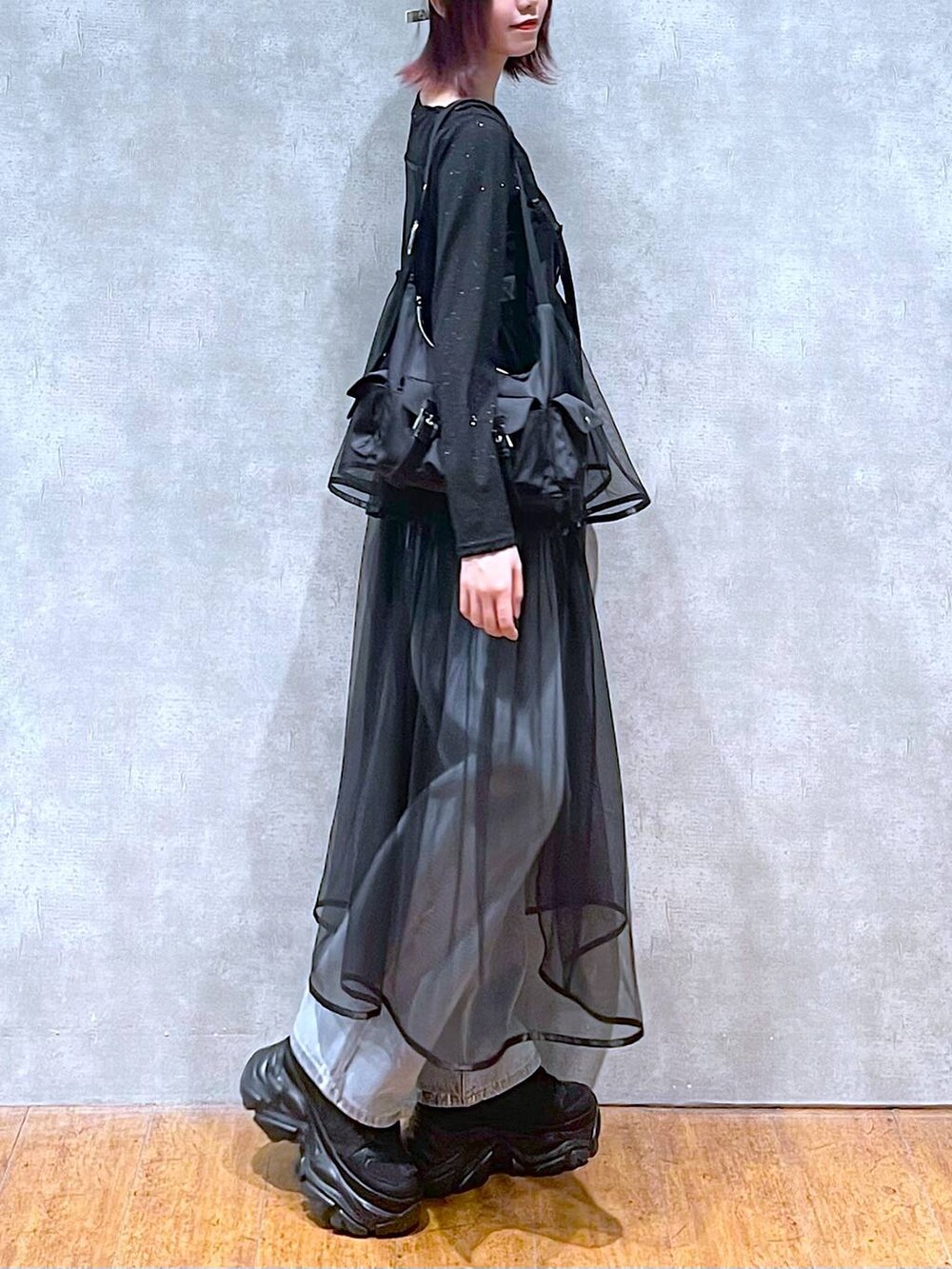 ブラック系のショルダーバッグ、ブラック系のスニーカー、ブルー系のデニムパンツを着用したレディースの春コーディネートの4枚目の写真