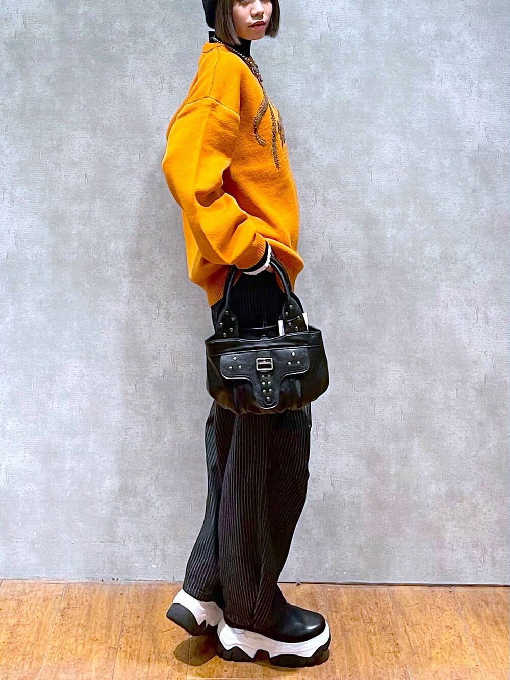 ブラック系のニット/セーター、ブラック系のデニムパンツ、ブラック系のハンドバッグを着用したレディースの秋コーディネートの5枚目の写真