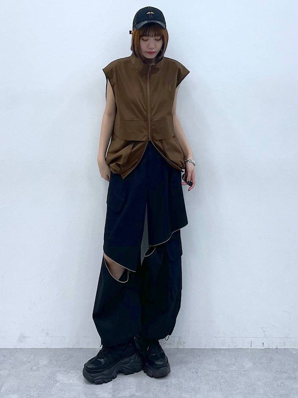 ブラック系のスニーカー、ブラック系のカーゴパンツ、ブラウン系のベストを着用したレディースの夏コーディネートの3枚目の写真