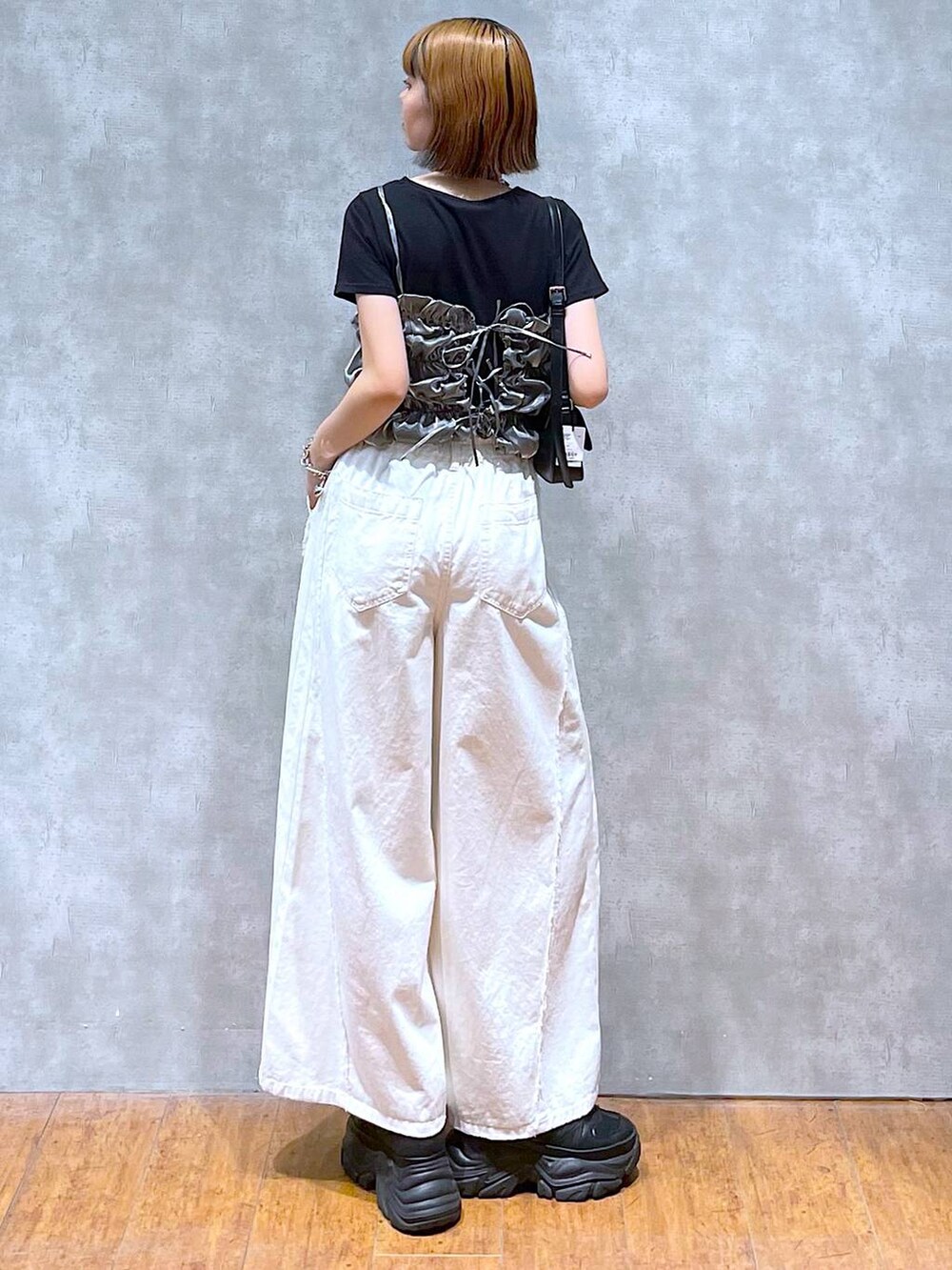 ブラック系のスニーカー、ホワイト系のデニムパンツ、ブラック系のハンドバッグを着用したレディースの夏コーディネートの3枚目の写真