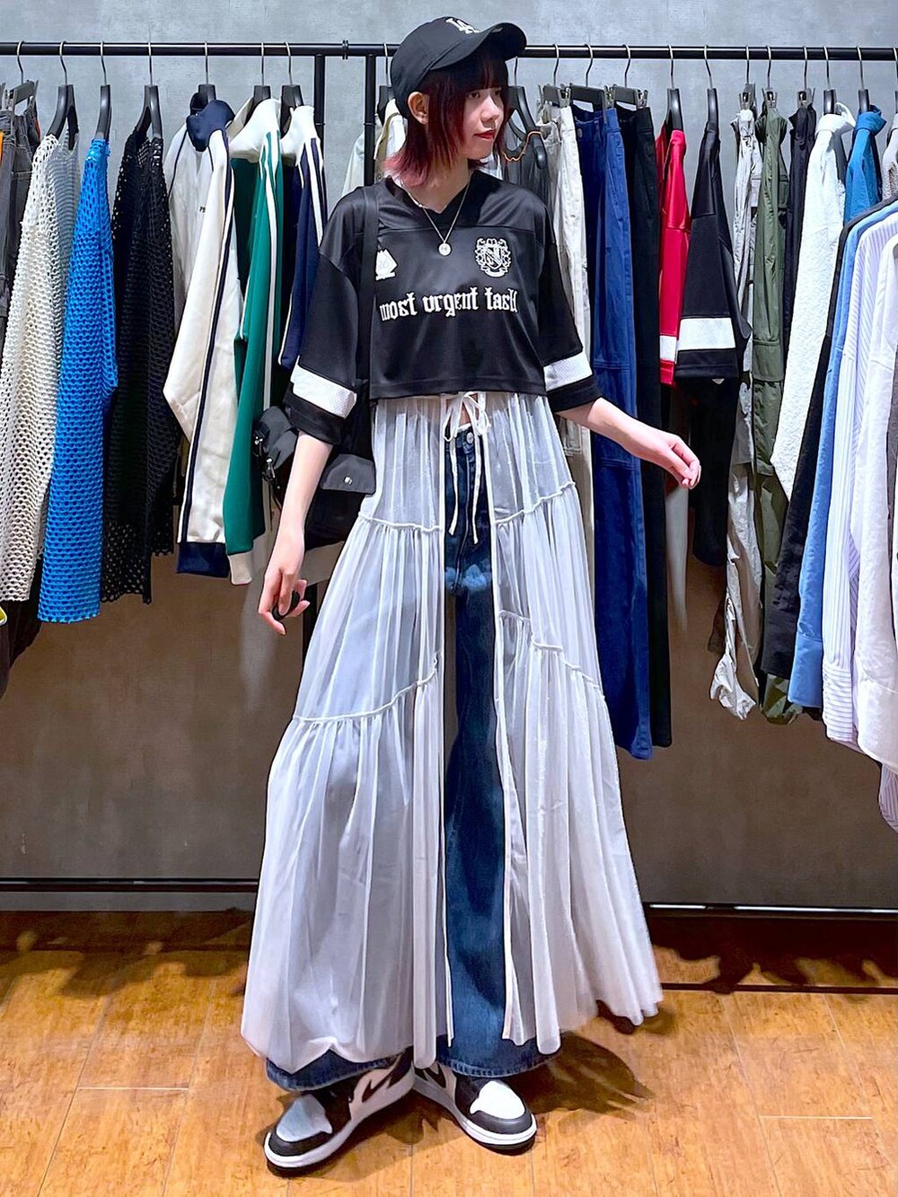 ブラック系のショルダーバッグ、ブルー系のデニムパンツ、ホワイト系のワンピースを着用したレディースの春コーディネートの3枚目の写真