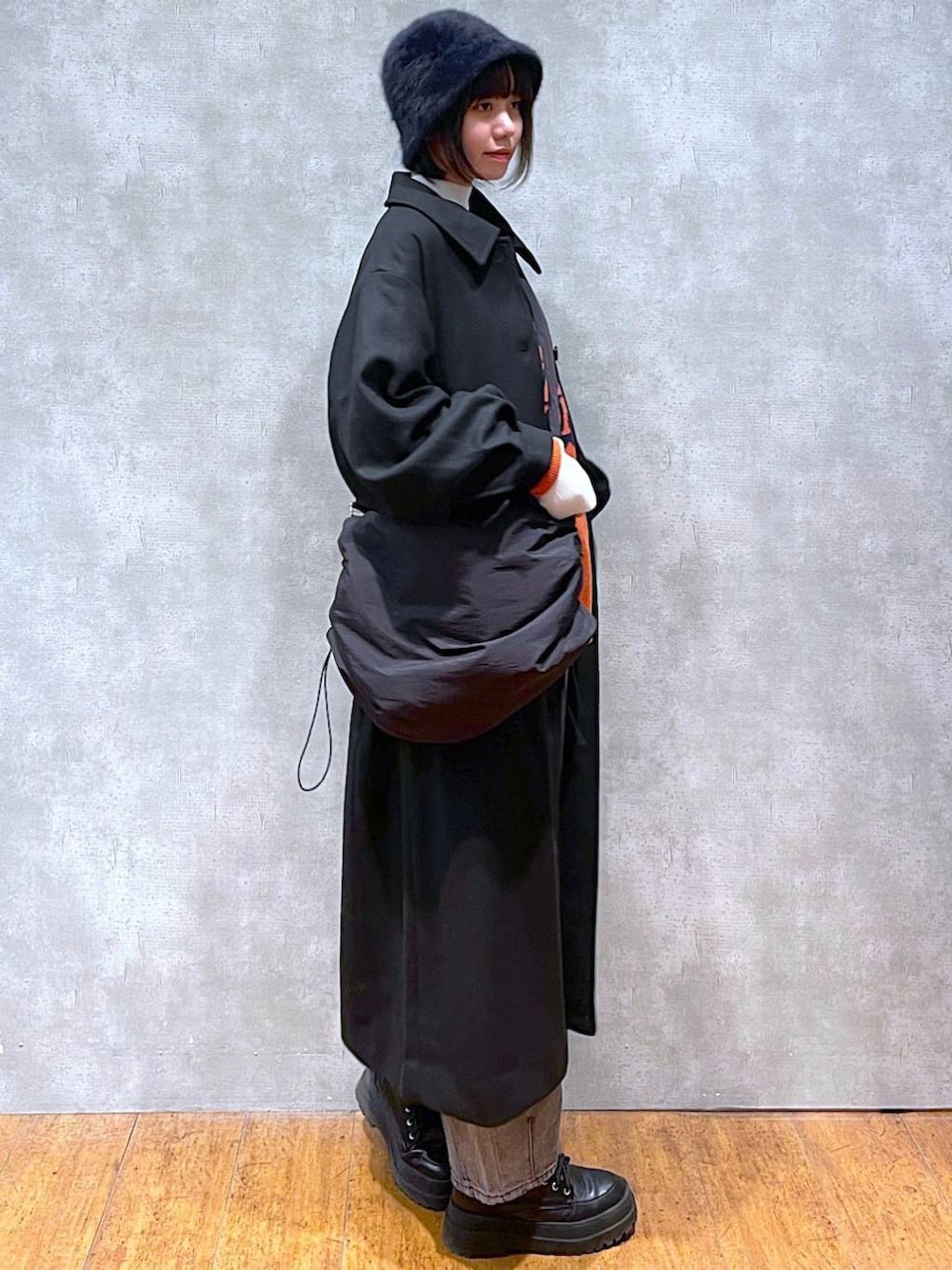 ブラック系のブーツ、ブラック系のチェスターコート、ブラック系のデニムパンツを着用したレディースの冬コーディネートの4枚目の写真